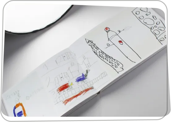 Nyitott füzetben gyerekrajz ceruzával, a Rajzkönyv ötletének jelképe.