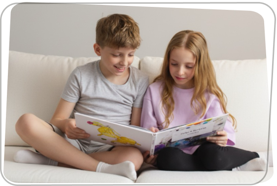 Két gyerek a kanapén ülve lapozza a saját rajzaikból készült Rajzkönyvet.